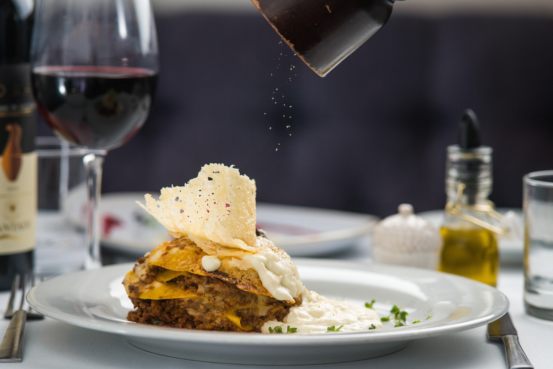 Lasaña emplatada en un restaurante, con parmesano recién rallado